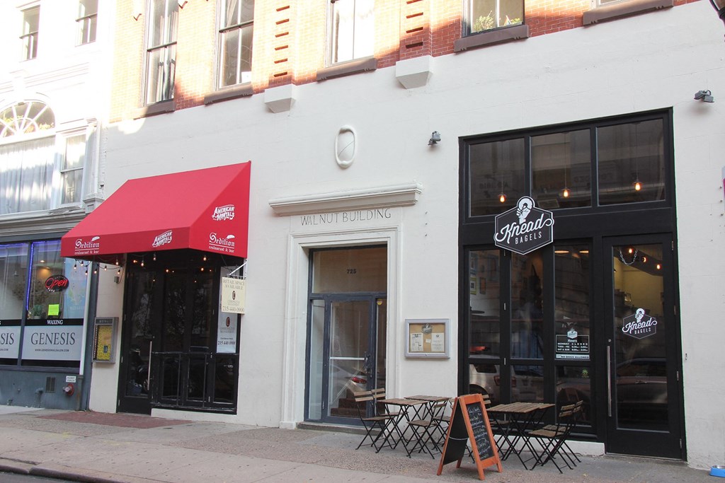 a white building with a red awning and tables outside of it