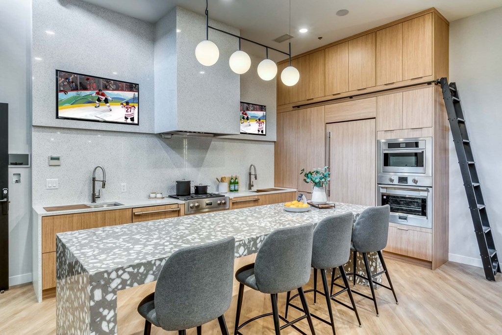 A kitchen with a table and chairs in the foreground and a television on the wall.
