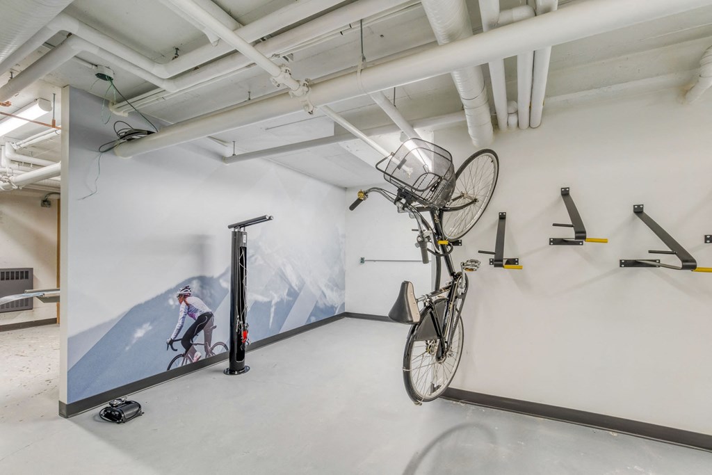 A bike is hanging from the ceiling in a room with a mural of a mountain and a cyclist.