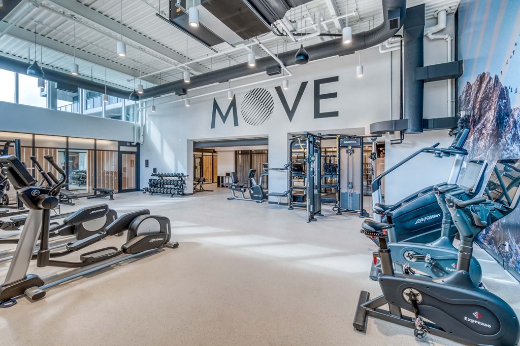 A gym with a variety of exercise equipment and a large "MOVE" sign on the wall.