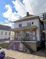 a picture of an old house with a car parked in front of it