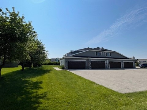 A large house with a garage is surrounded by a green lawn.