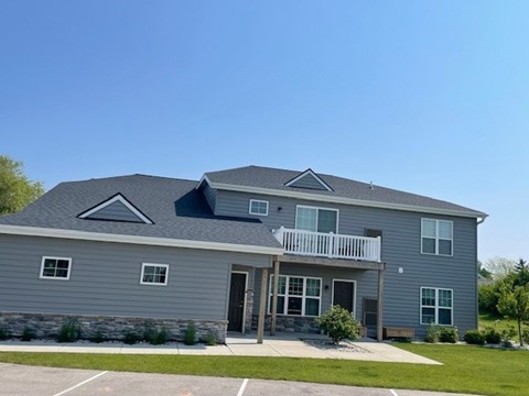A grey house with a black roof and a balcony.
