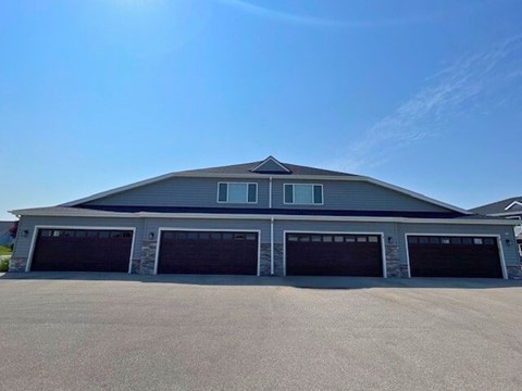 A large two-story building with a grey roof and four garage doors.