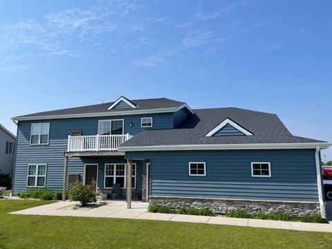 A blue house with a grey roof and a white fence.