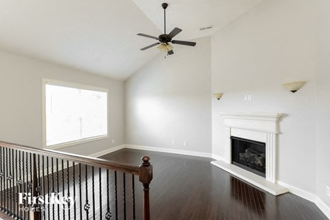 A living room with a fireplace and a ceiling fan.