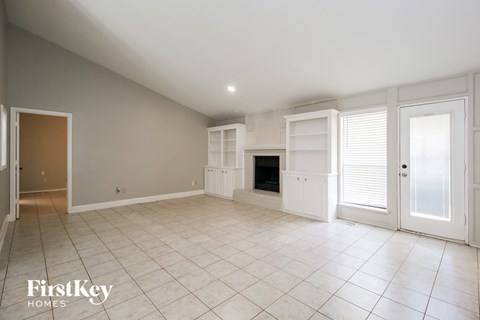 A spacious room with a fireplace and a door on the left.