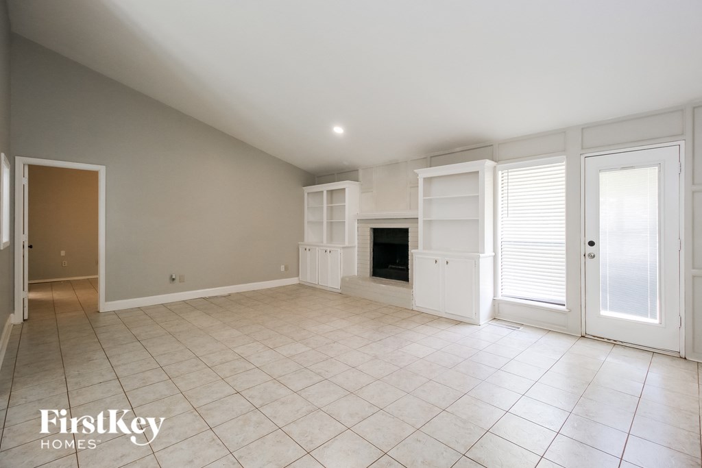 A spacious room with a fireplace and a door on the left.