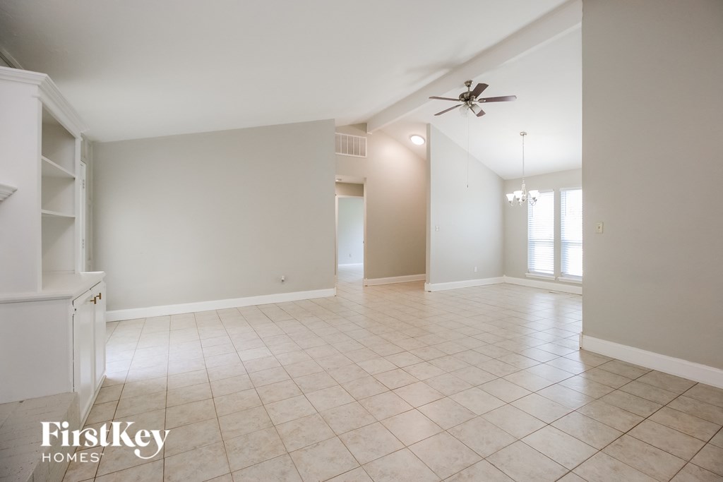 A spacious room with a ceiling fan and tiled flooring.