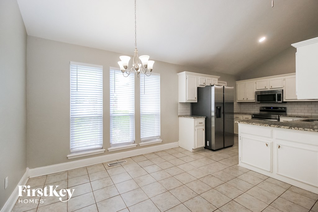 A kitchen with white cabinets and a black refrigerator.