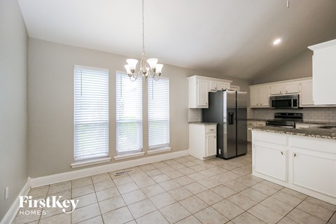A kitchen with white cabinets and a black refrigerator.