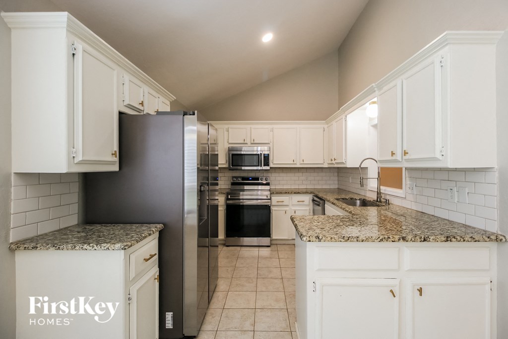 A kitchen with a granite counter top and a refrigerator.