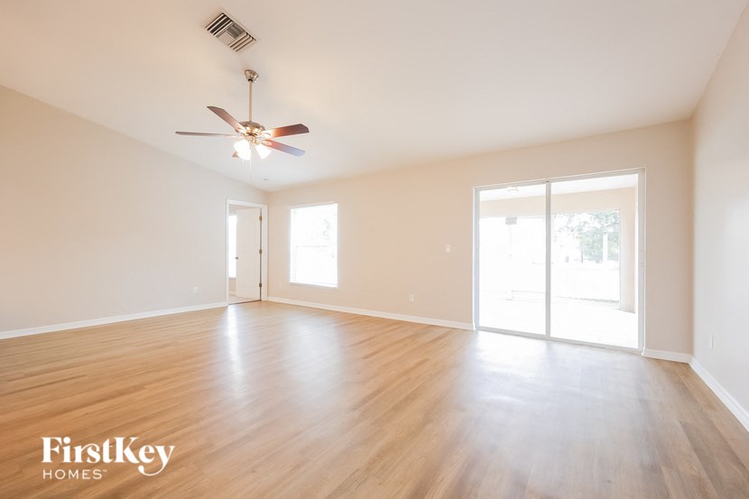 an empty living room with wood floors and a ceiling fan