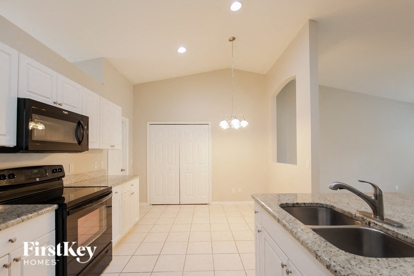 a kitchen with white cabinets and black appliances and a sink