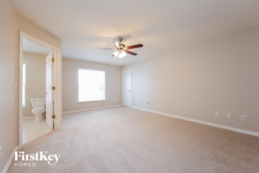 an empty living room with a ceiling fan and a toilet