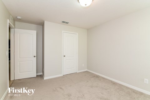 A bedroom with two doors and a carpeted floor.