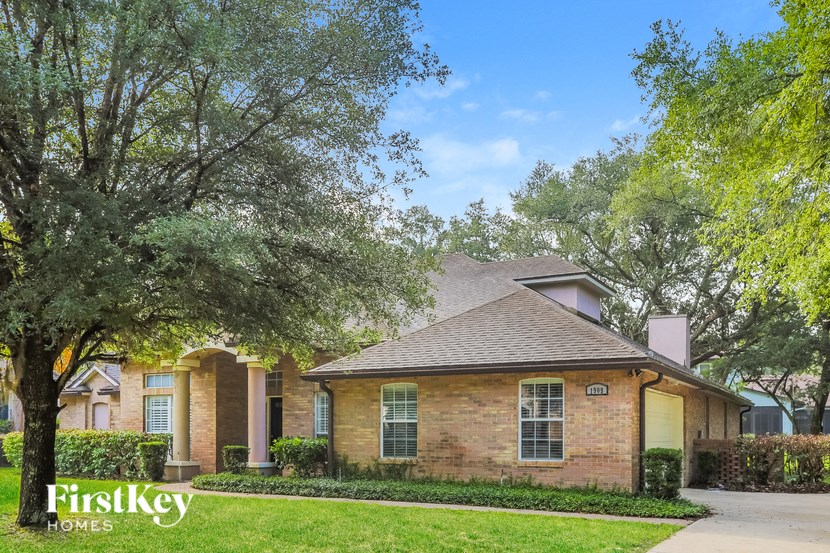 a brick house with trees and a sidewalk