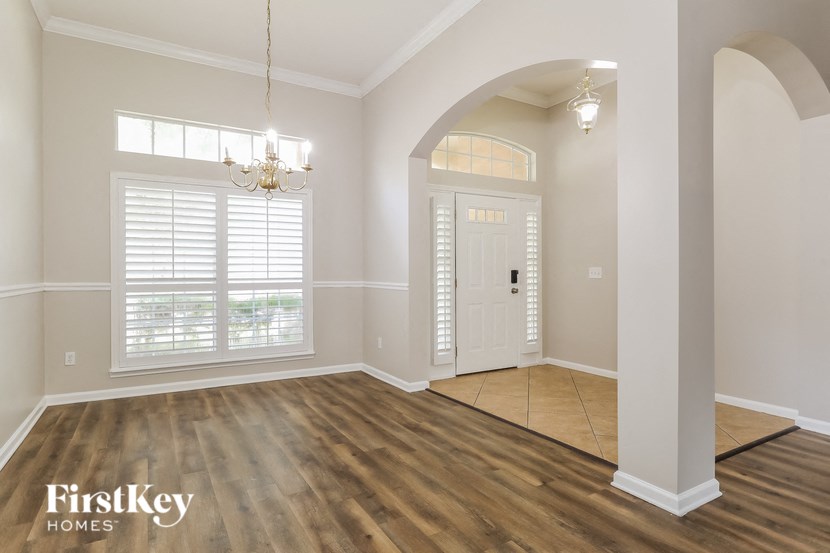 the living room and dining room of a house with wood floors and a white door
