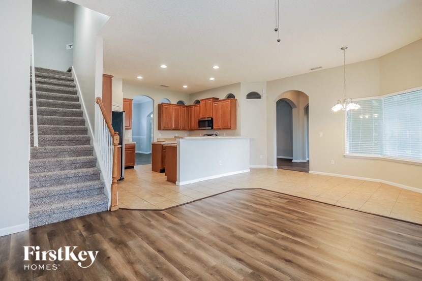 an empty living room with a staircase and a kitchen