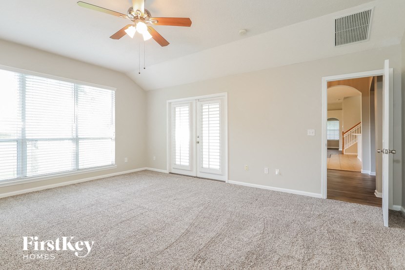 an empty living room with a ceiling fan and two windows