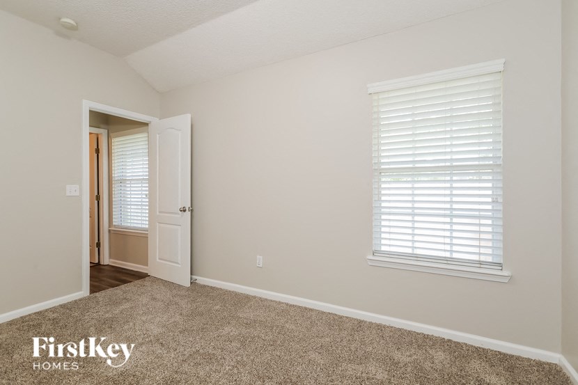 a bedroom with a carpeted floor and a door to a hallway