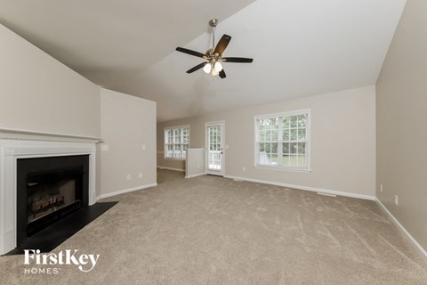 A spacious living room with a fireplace and a ceiling fan.