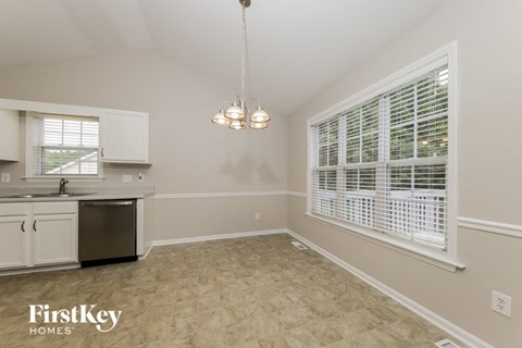 A kitchen with a dishwasher, sink, and a window with blinds.