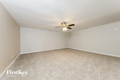 A room with a ceiling fan and carpeted floor.