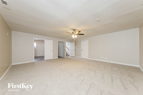A spacious room with a ceiling fan and carpeted floor.