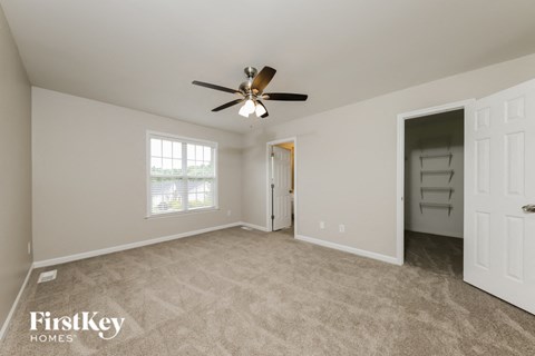 A spacious room with a ceiling fan and a door leading to another room.