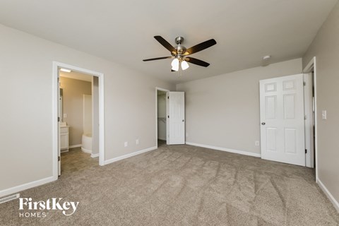 A spacious room with a ceiling fan and carpeted floor.