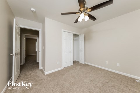 A spacious room with a ceiling fan and two doors.