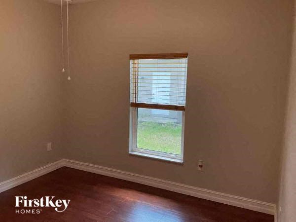 an empty room with a window and wooden floors