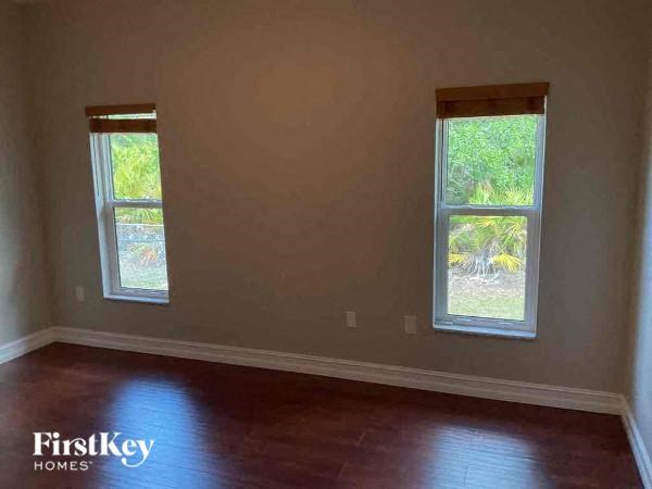 a empty room with two windows and a wooden floor