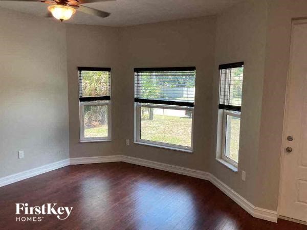 a living room with a hard wood floor and three windows