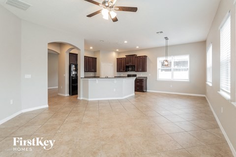 A spacious living room with a ceiling fan and tiled flooring.