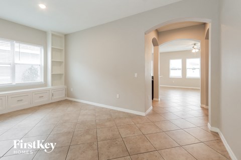 A spacious room with a tiled floor and a large archway leading to another room.