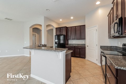 A kitchen with a white island and brown cabinets.