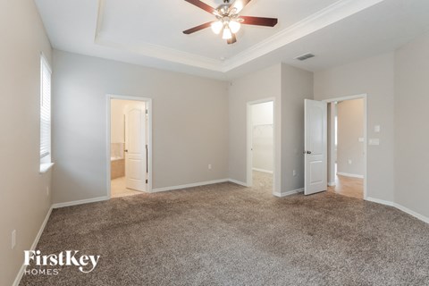 A spacious room with a ceiling fan and carpeted floor.