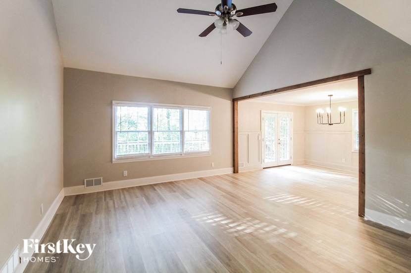 the living room and dining room with hardwood floors and a ceiling fan