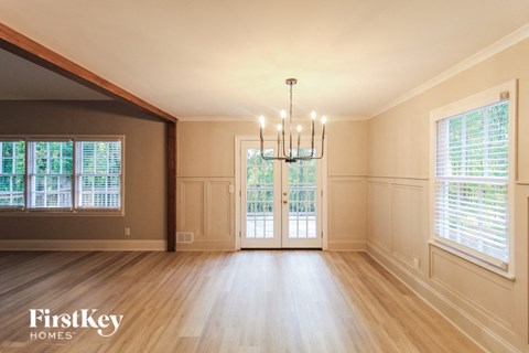 an empty dining room with a chandelier and windows