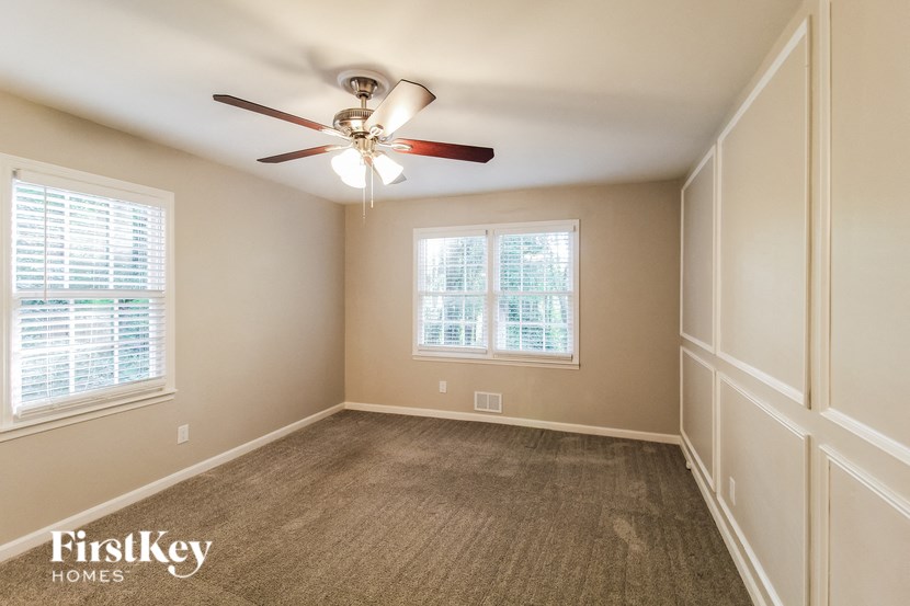 an empty room with a ceiling fan and two windows