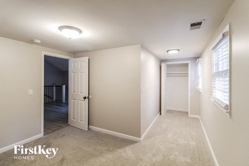 an empty hallway with a door to a closet and a hallway leading to a room