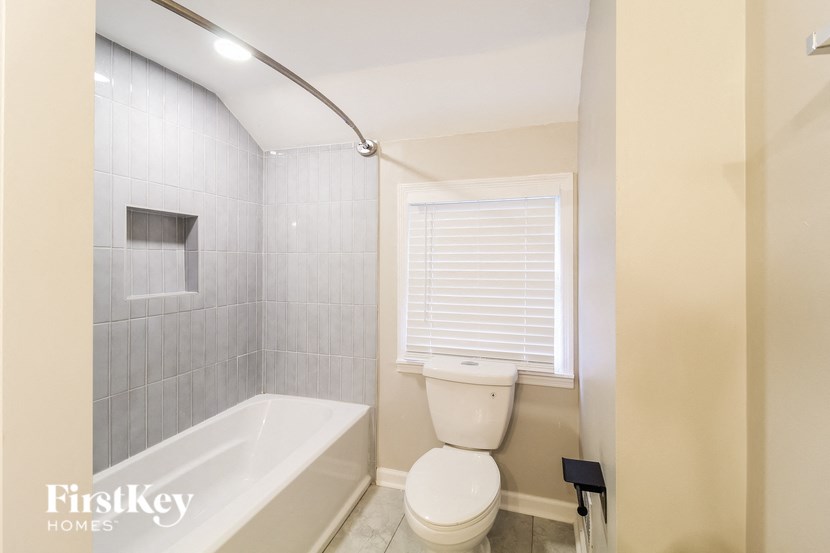 a bathroom with a toilet and a tub and a window