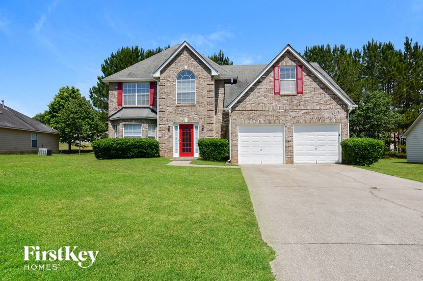 a brick house with red doors and a white garage door