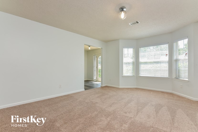 an empty living room with large windows and a carpeted floor