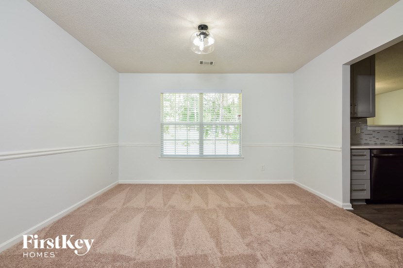 an empty living room with a window and a kitchen