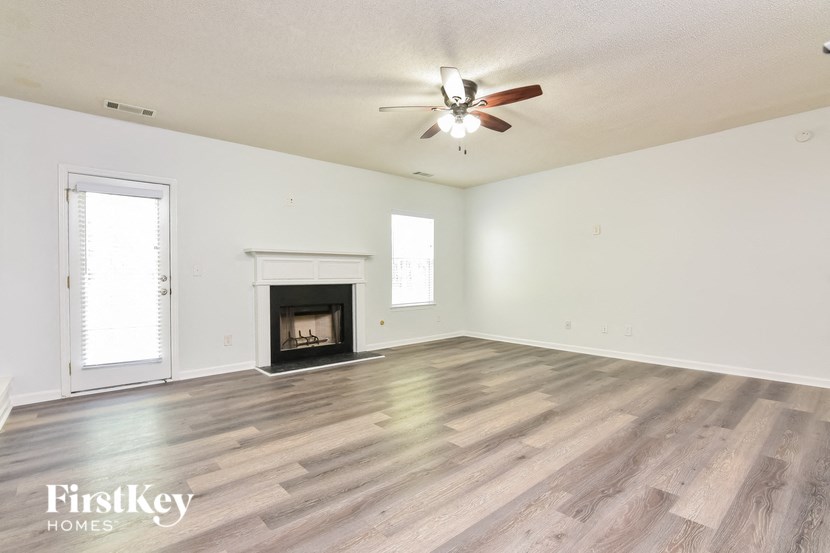 an empty living room with a fireplace and a ceiling fan
