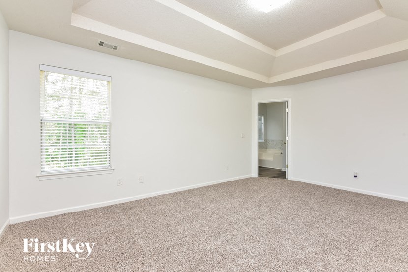 an empty living room with a large window and carpet