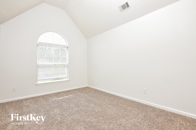 an empty bedroom with a window and carpet